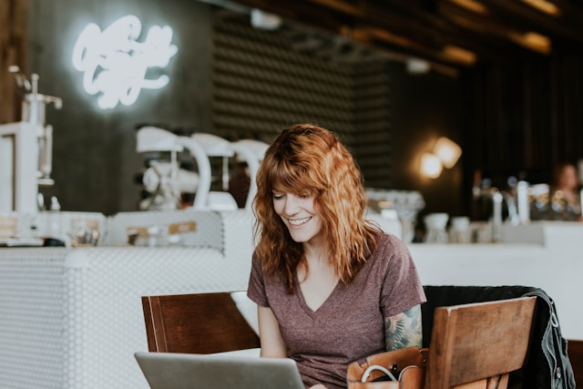 A woman is sitting on a comfortable chair with a laptop, working remotely and maintaining good mental health.